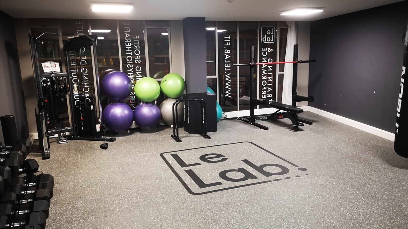 Salle d'exercices du Lab avec ballons, haltères et logo Le Lab au sol